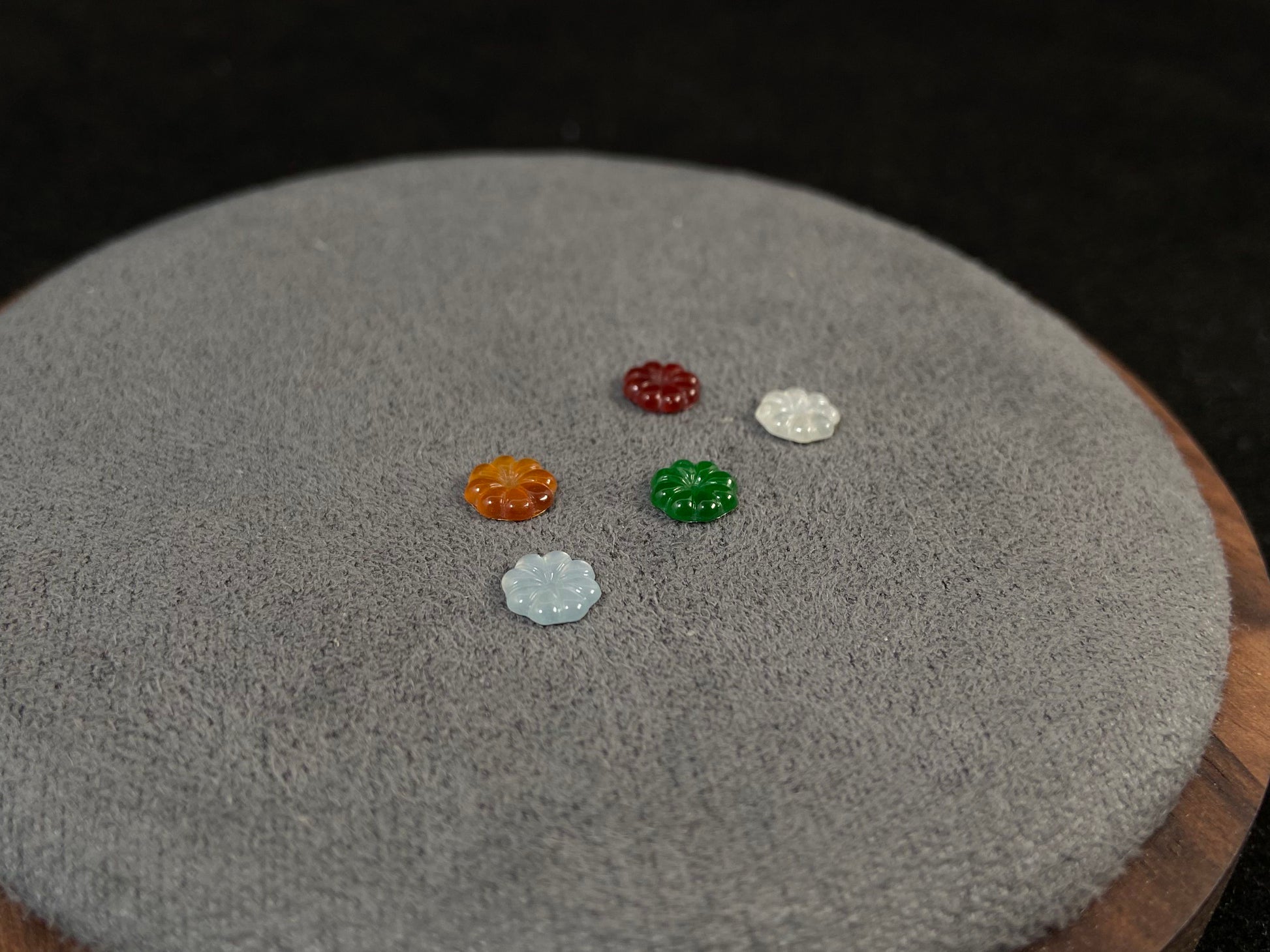 Five sunflowers carved from jade in white, green, yellow, red, and blue.
