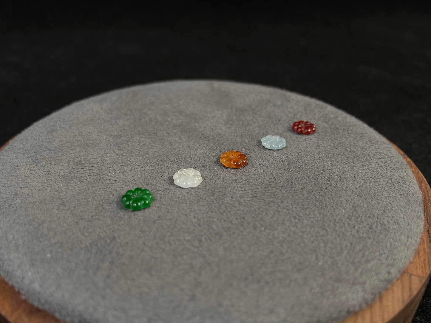 Five sunflowers carved from jade in white, green, yellow, red, and blue.