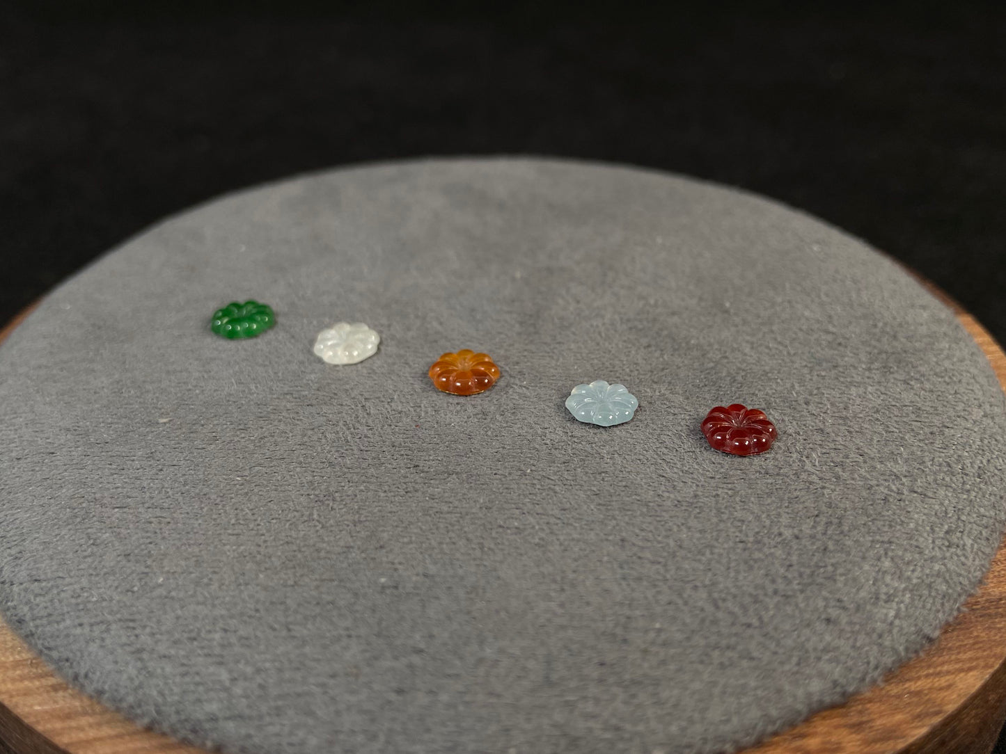 Five sunflowers carved from jade in white, green, yellow, red, and blue.