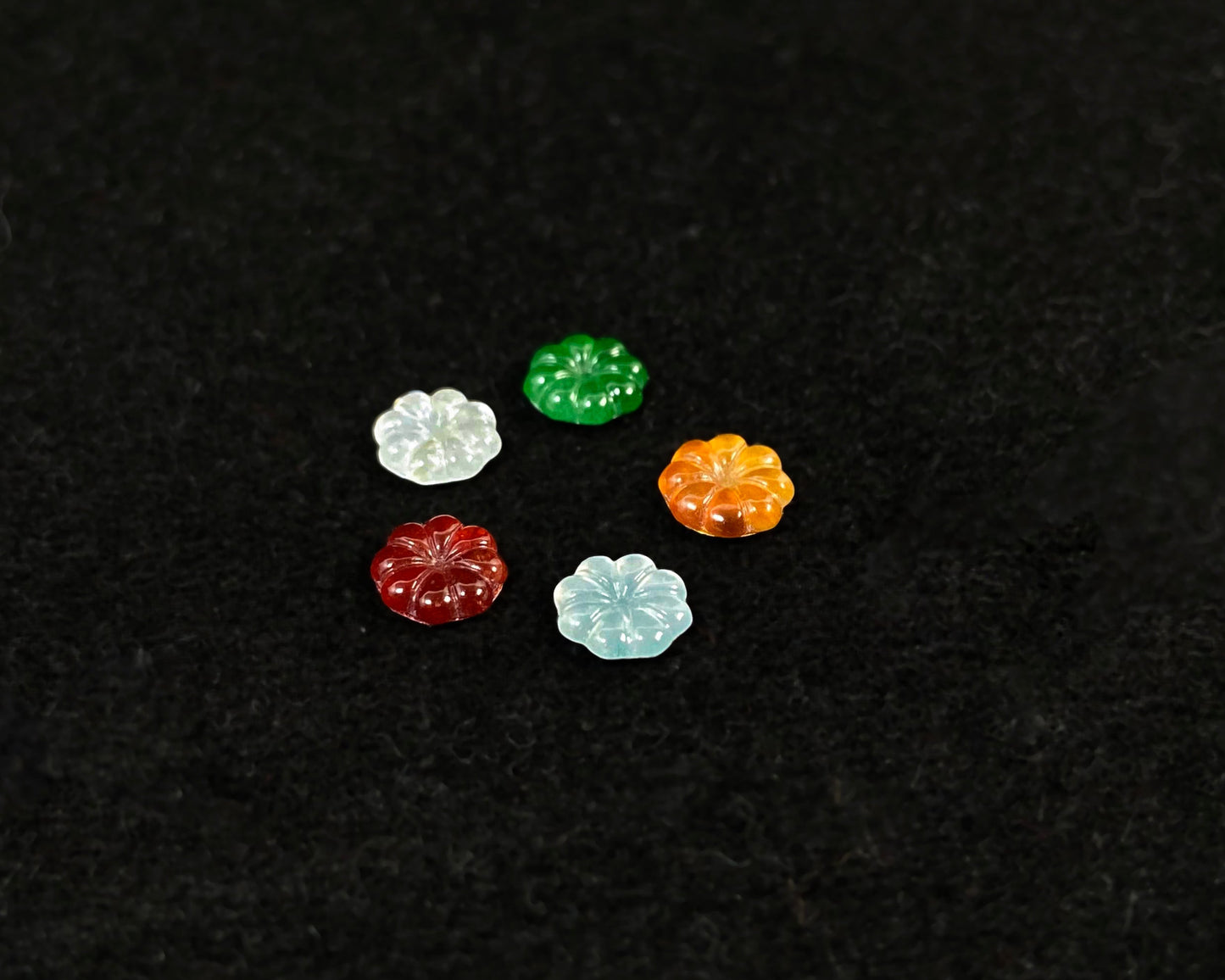 Five sunflowers carved from jade in white, green, yellow, red, and blue.