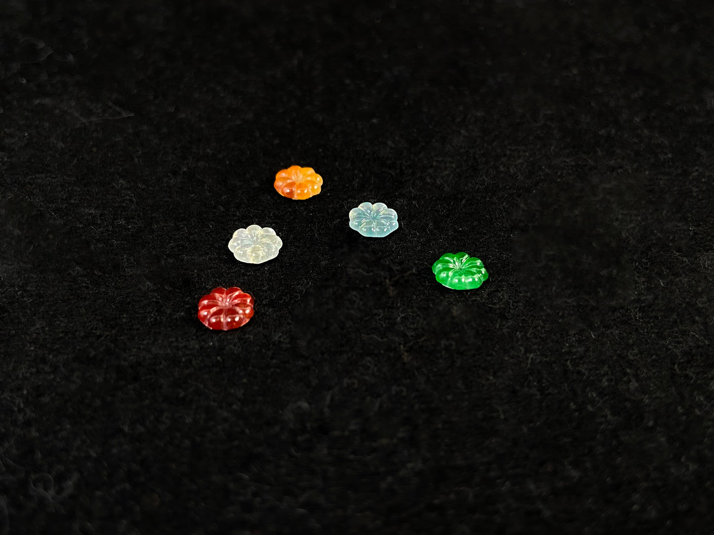 Five sunflowers carved from jade in white, green, yellow, red, and blue.