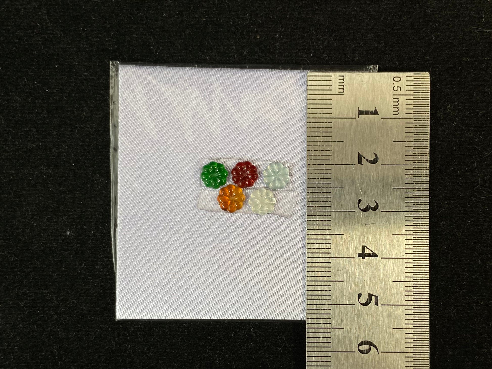 Five sunflowers carved from jade in white, green, yellow, red, and blue.