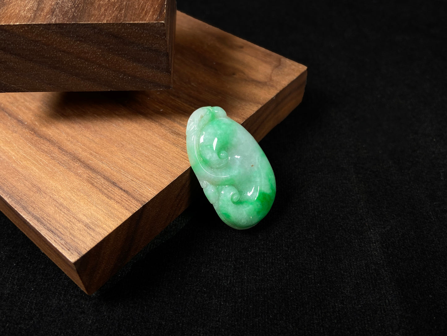 A milky white jadeite loose stone with floating apple green patterns, carved into a Ruyi symbol.