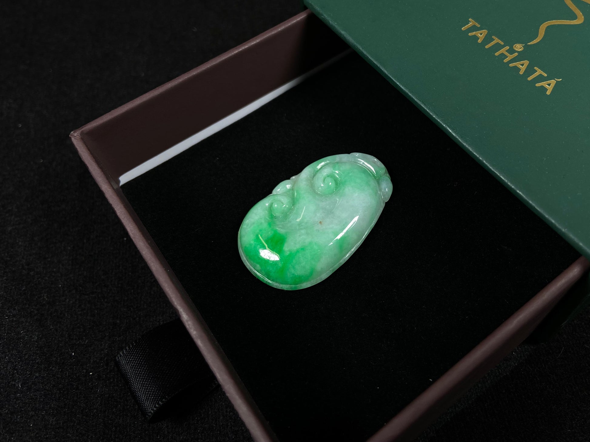 A milky white jadeite loose stone with floating apple green patterns, carved into a Ruyi symbol.