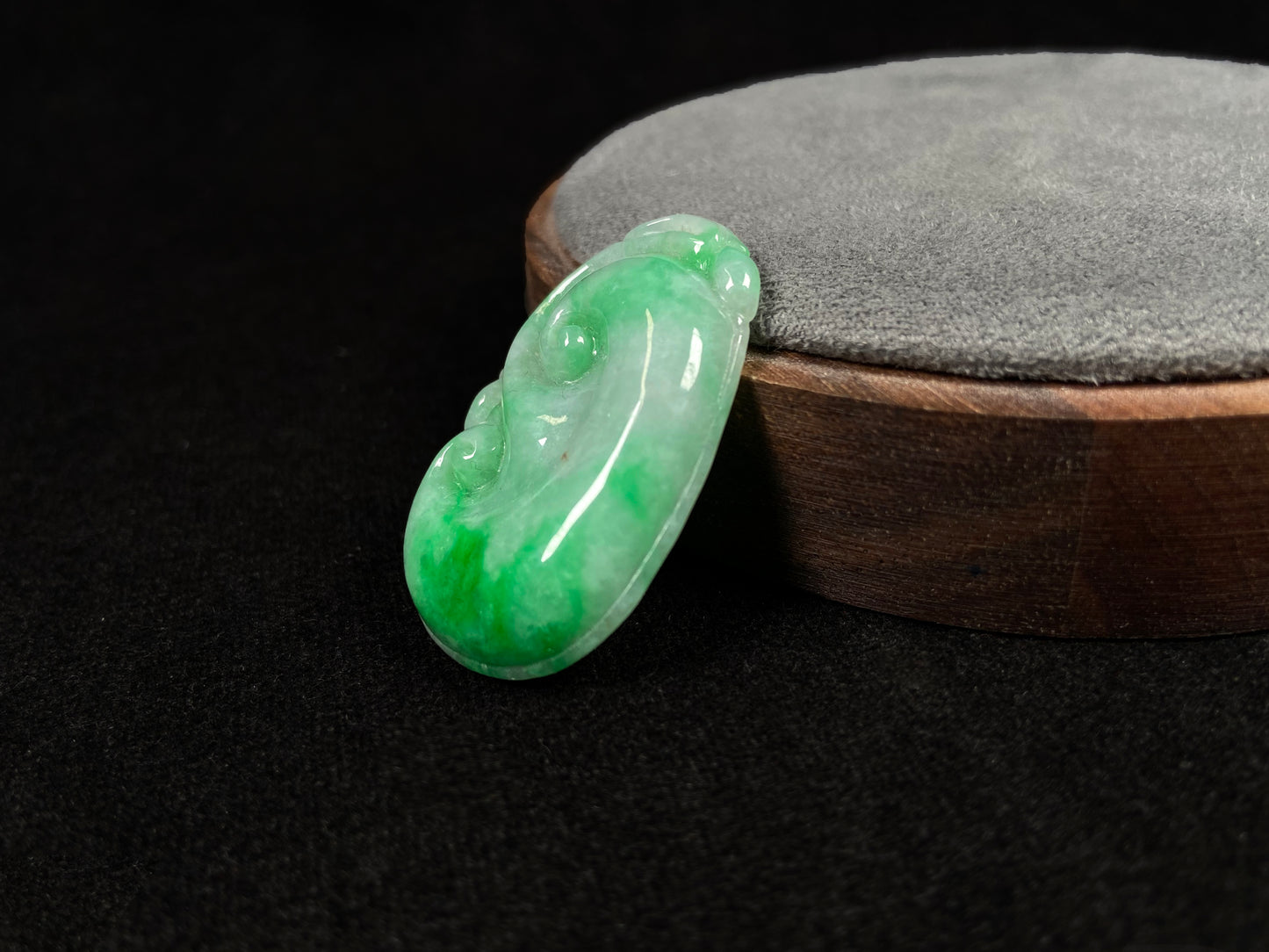 A milky white jadeite loose stone with floating apple green patterns, carved into a Ruyi symbol.