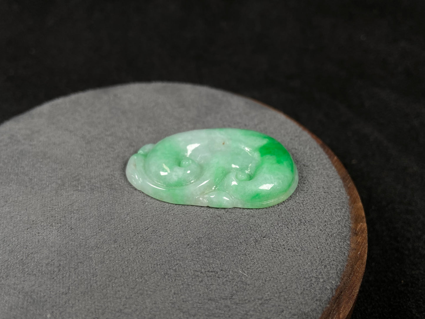 A milky white jadeite loose stone with floating apple green patterns, carved into a Ruyi symbol.