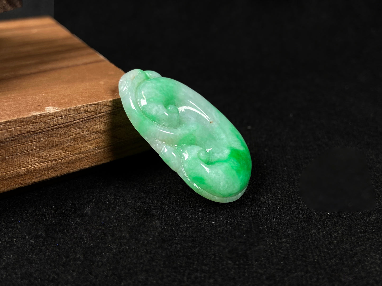 A milky white jadeite loose stone with floating apple green patterns, carved into a Ruyi symbol.
