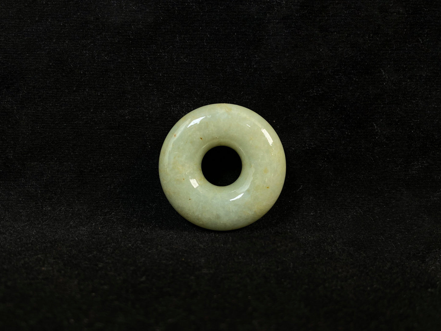 A light green jade donut-shaped stone with golden accents.