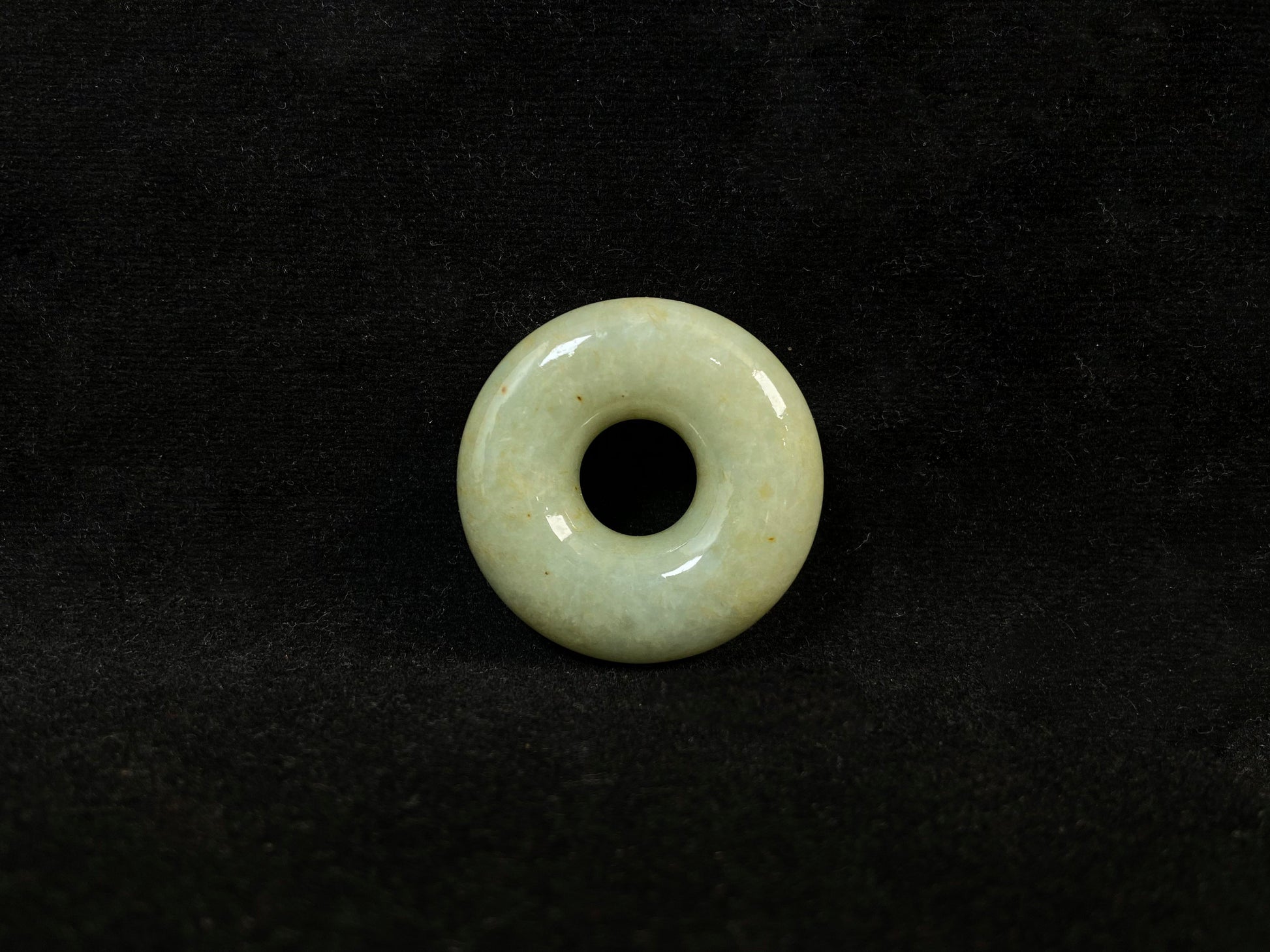 A light green jade donut-shaped stone with golden accents.