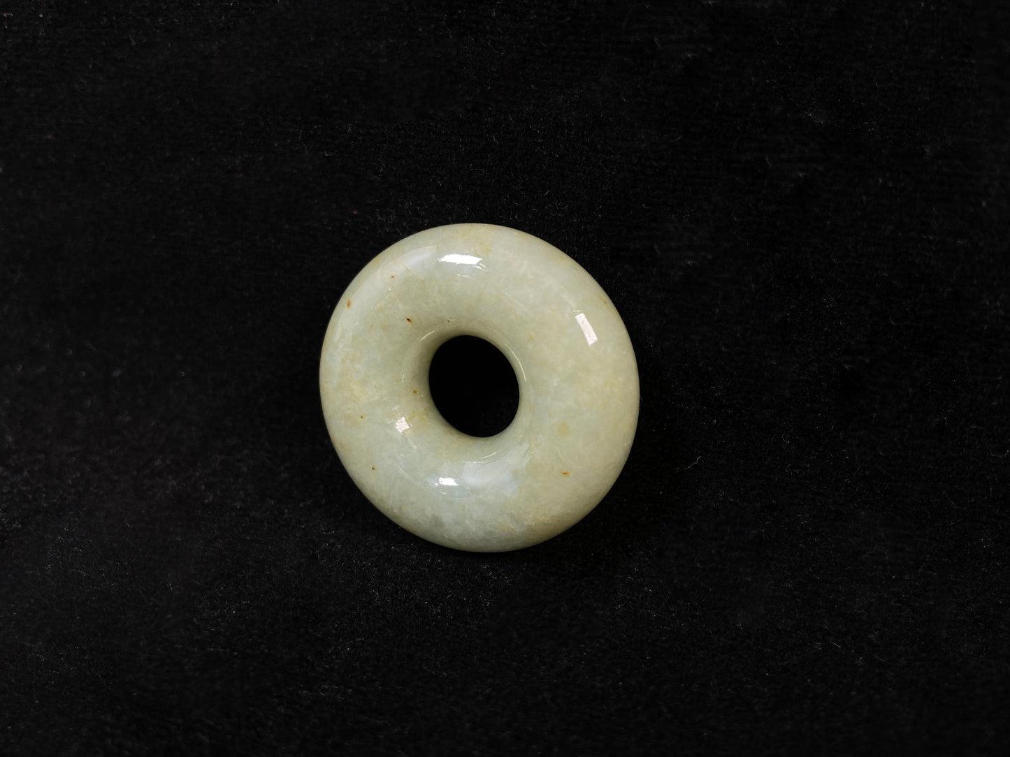 A light green jade donut-shaped stone with golden accents.