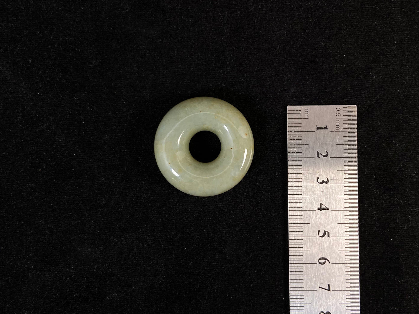 A light green jade donut-shaped stone with golden accents.