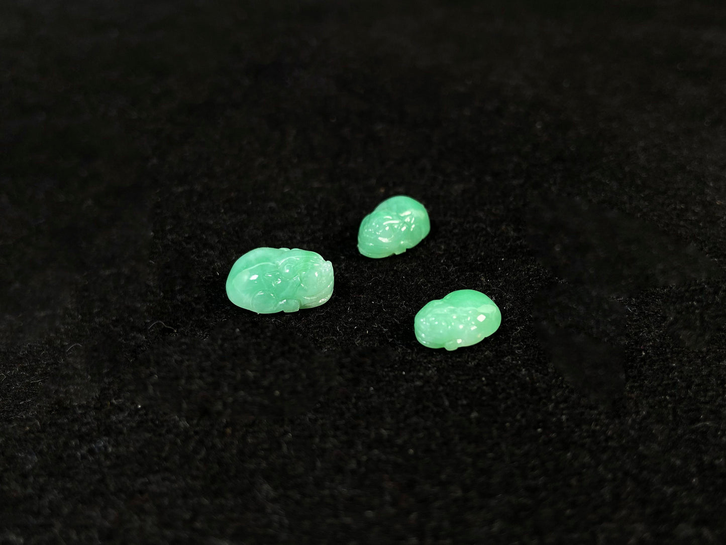 Three green Pixiu carvings of varying sizes, crafted from jade.