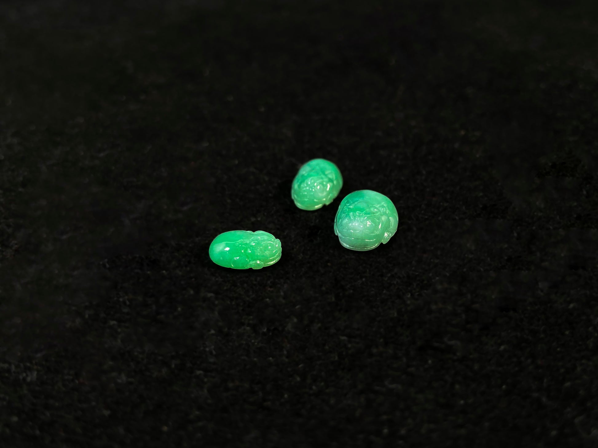 Three green Pixiu carvings of varying sizes, crafted from jade.