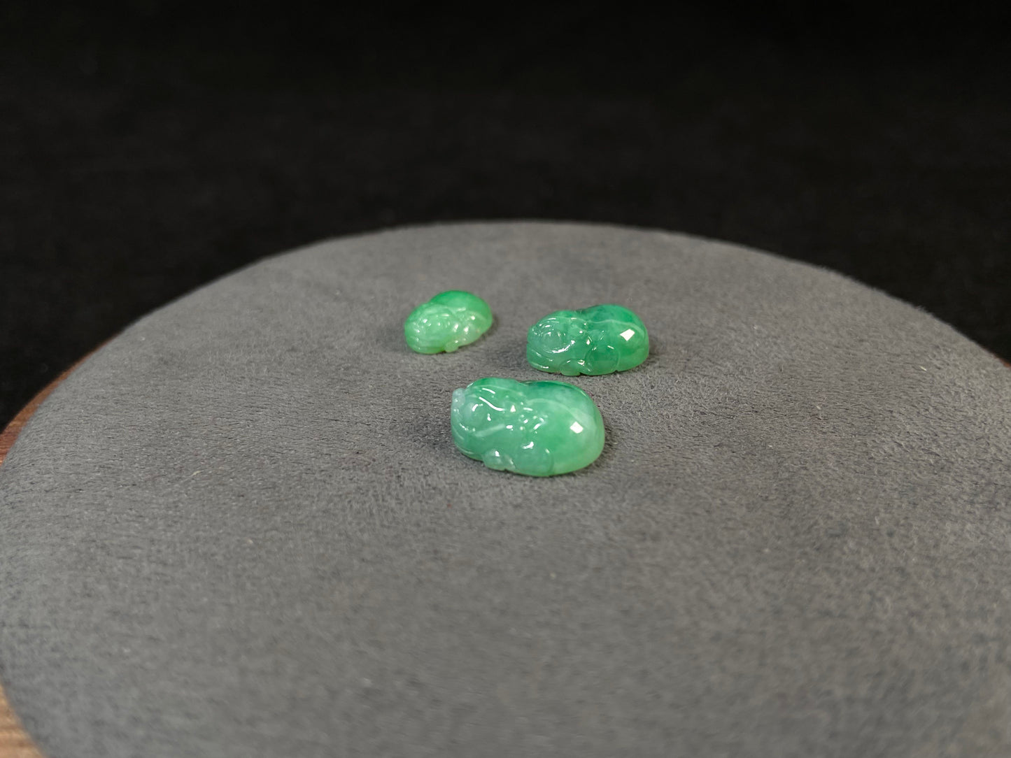 Three green Pixiu carvings of varying sizes, crafted from jade.