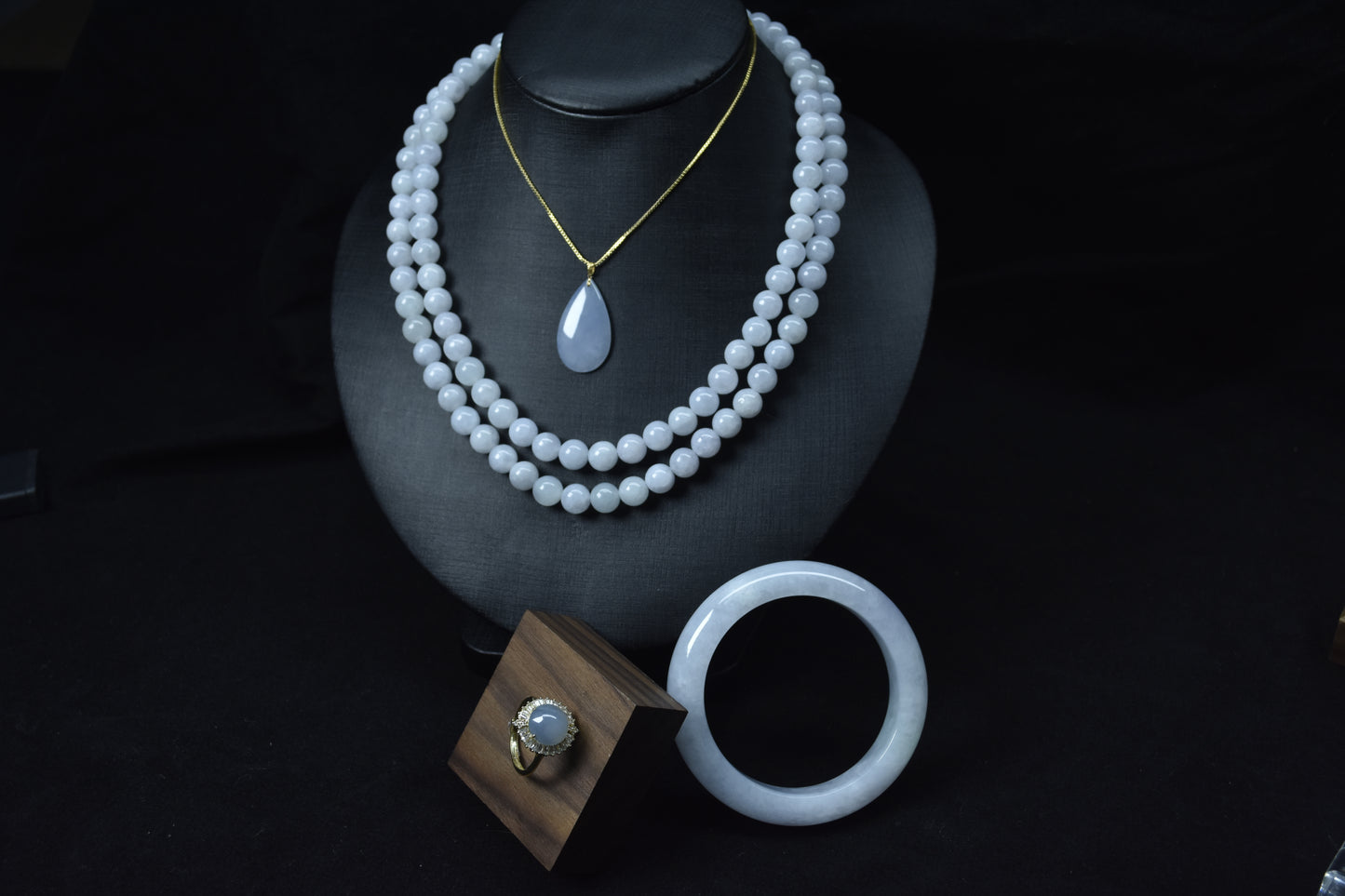Set of white jade jewelry including necklace, ring, and bracelet on a black background