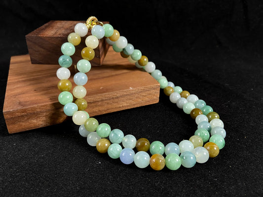 A jade bead strand featuring green, brown, pale yellow, white, and bluish purple beads.