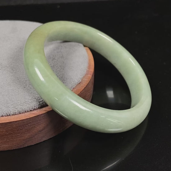 A light green base with warm golden hues jadeite bangle.