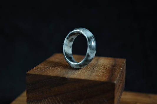 Silver ring on a wooden block with a dark background