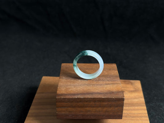 A milky white jadeite ring featuring a single stroke of deep green.