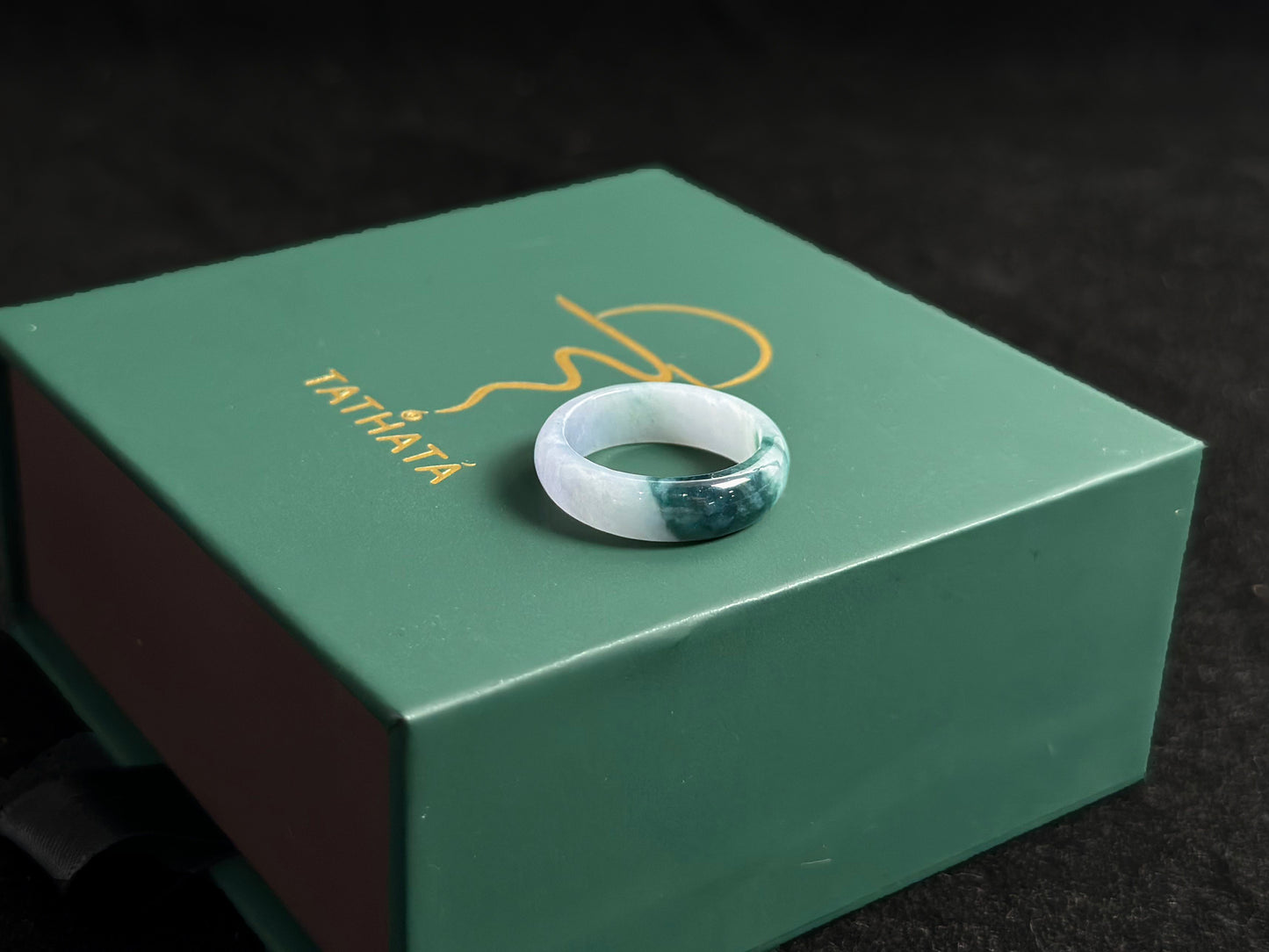 A milky white jadeite ring featuring a single stroke of deep green.