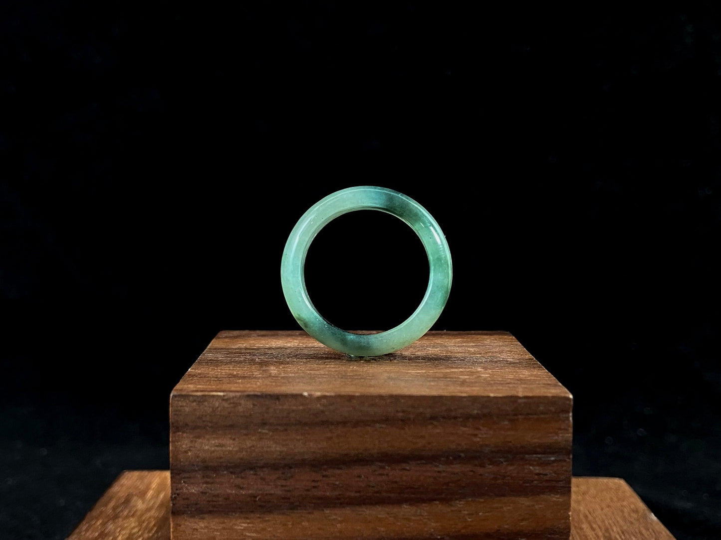 A pale green jadeite ring with elegant dark grey-green accents.