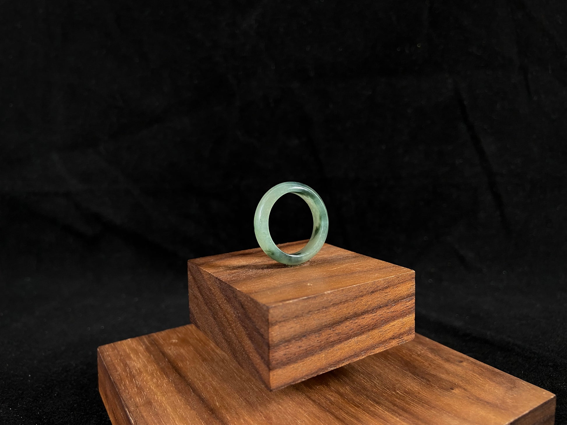 A pale green jadeite ring with elegant dark grey-green accents.