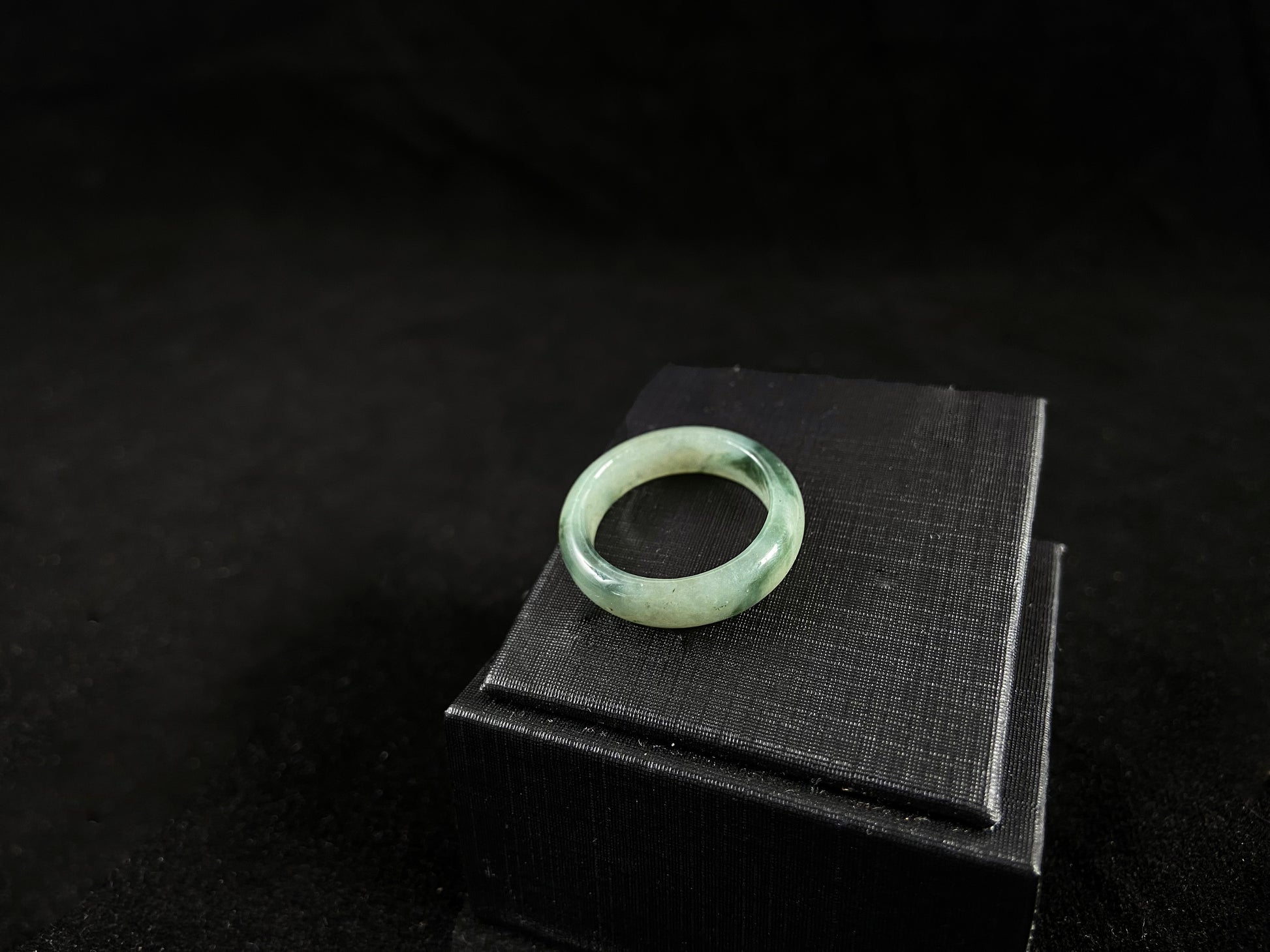 A pale green jadeite ring with elegant dark grey-green accents.