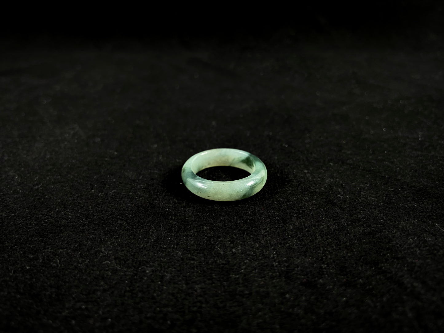 A pale green jadeite ring with elegant dark grey-green accents.