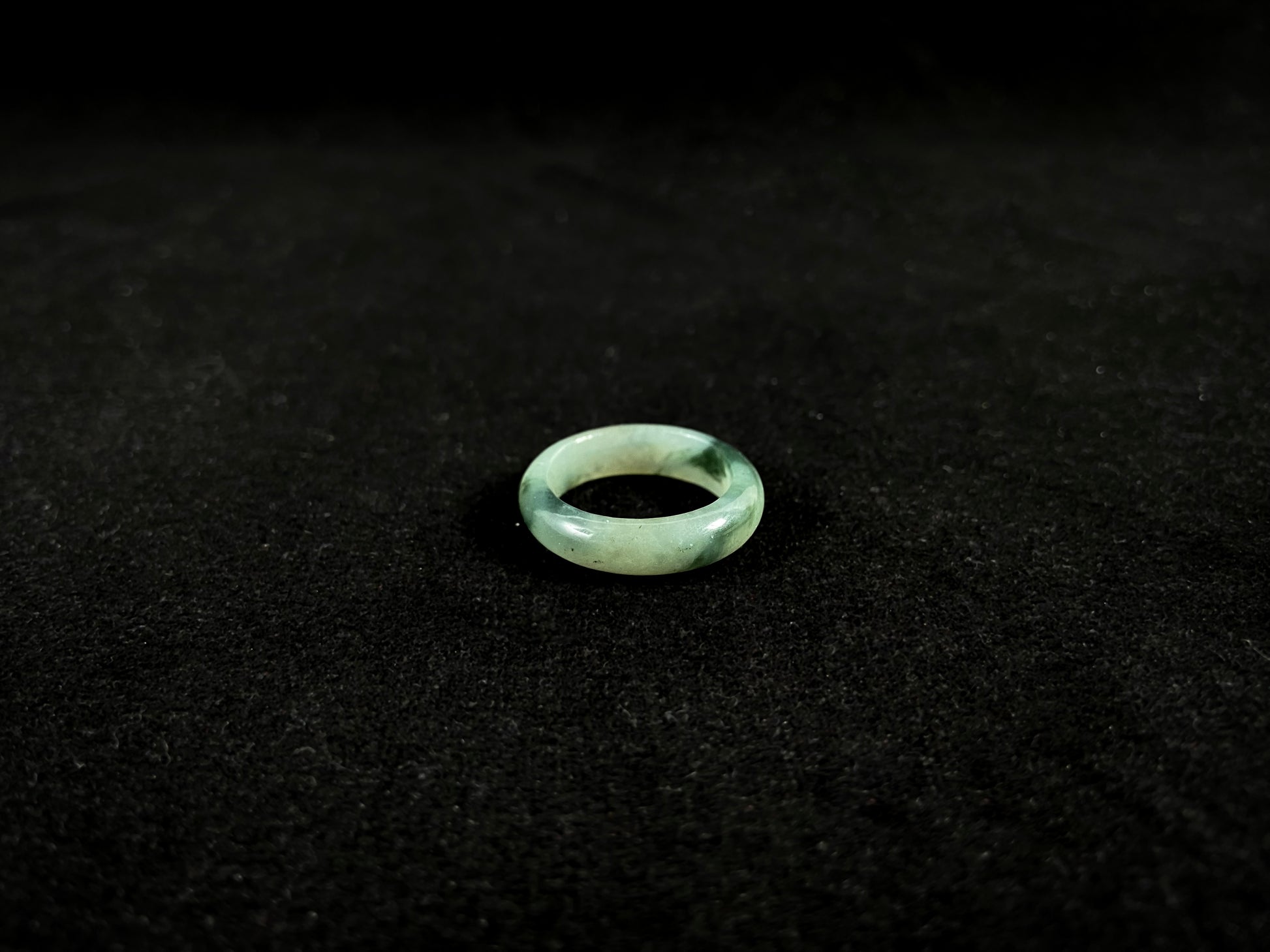 A pale green jadeite ring with elegant dark grey-green accents.