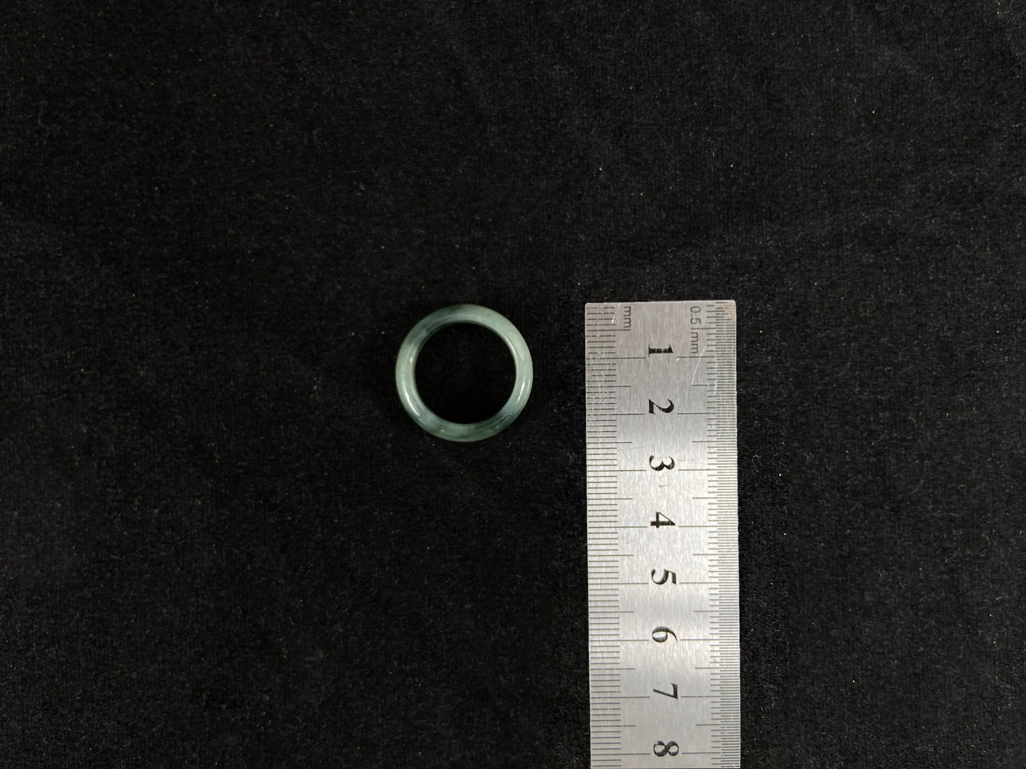 A pale green jadeite ring with elegant dark grey-green accents.