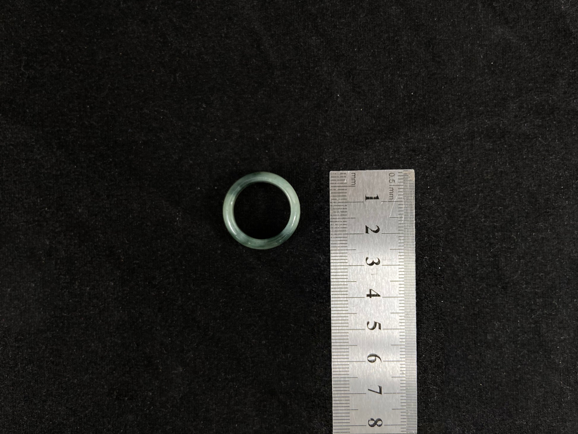 A pale green jadeite ring with elegant dark grey-green accents.