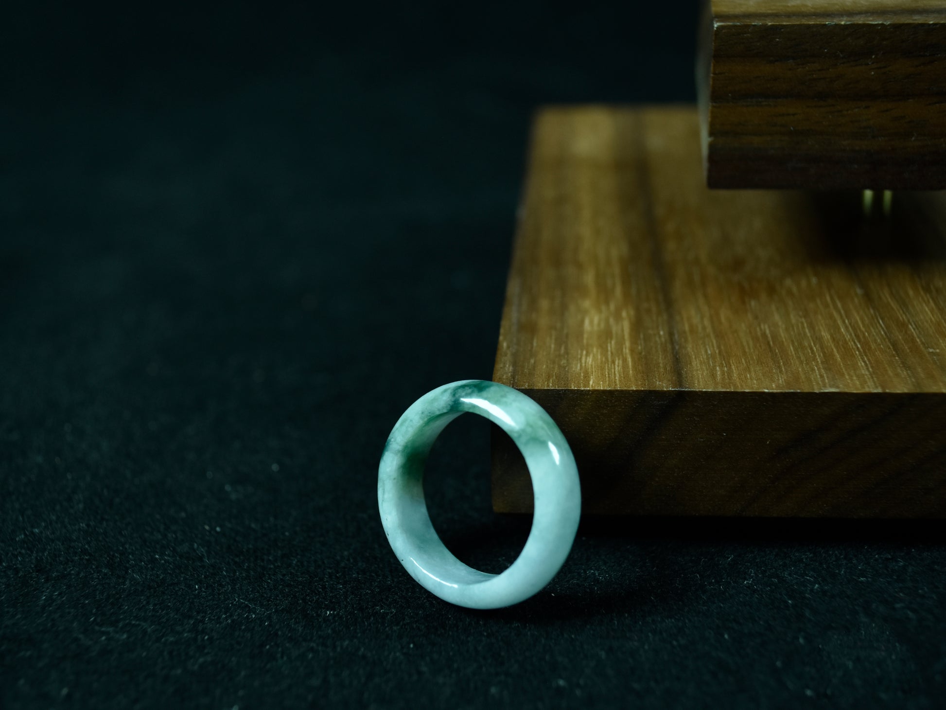 Jade ring on a dark surface with a wooden stand