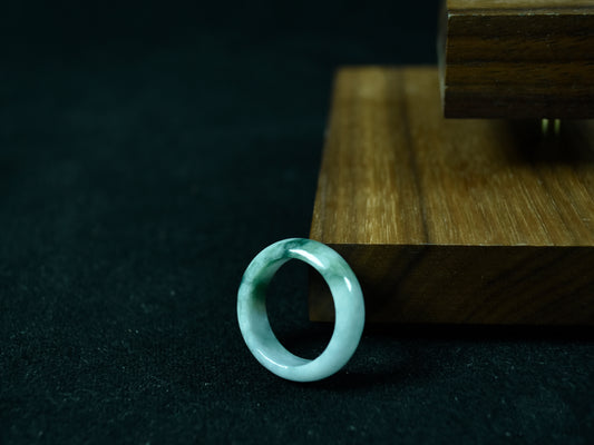 Jade ring on a dark surface with a wooden stand