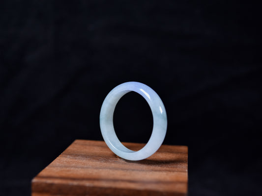 Translucent jade ring on a wooden stand with a dark background
