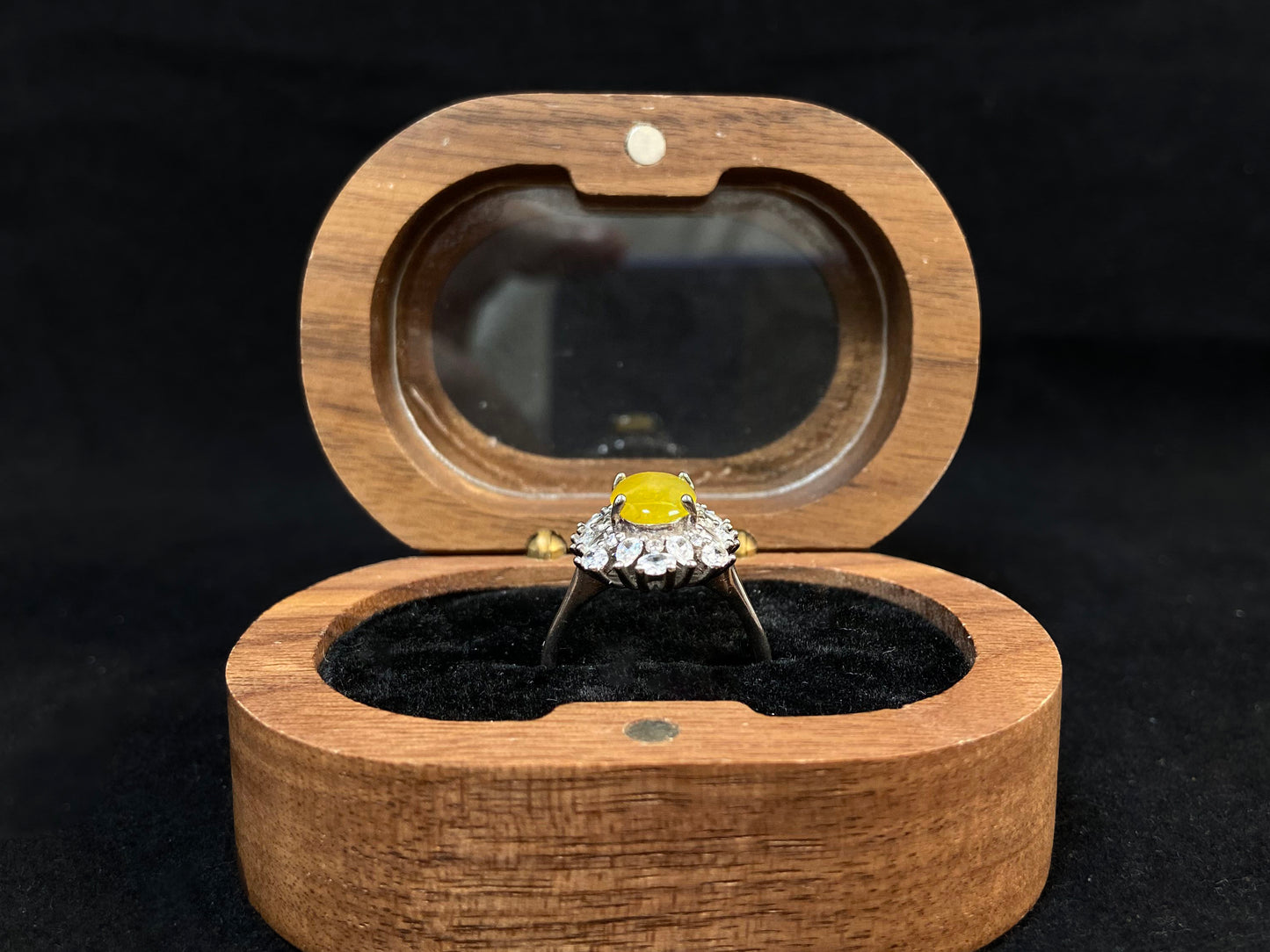 Stunning oval yellow jade is showcased in a diamond paved 925 silver setting.