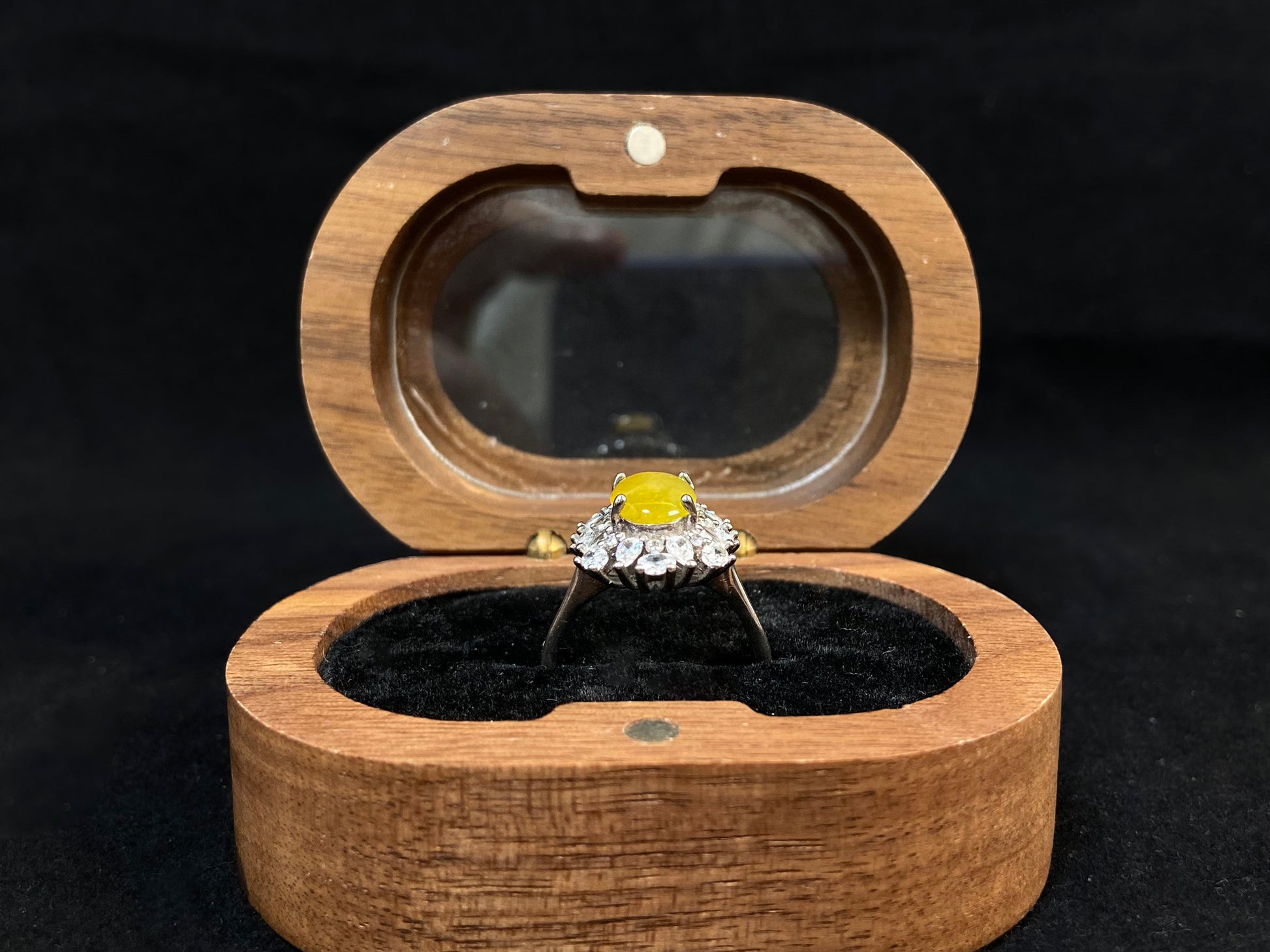 Stunning oval yellow jade is showcased in a diamond paved 925 silver setting.