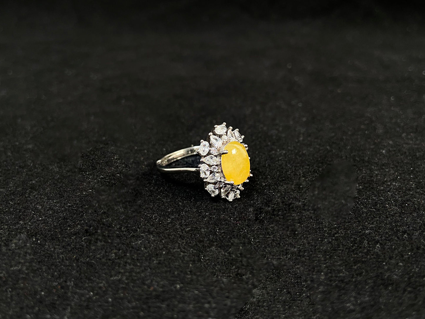 Stunning oval yellow jade is showcased in a diamond paved 925 silver setting.