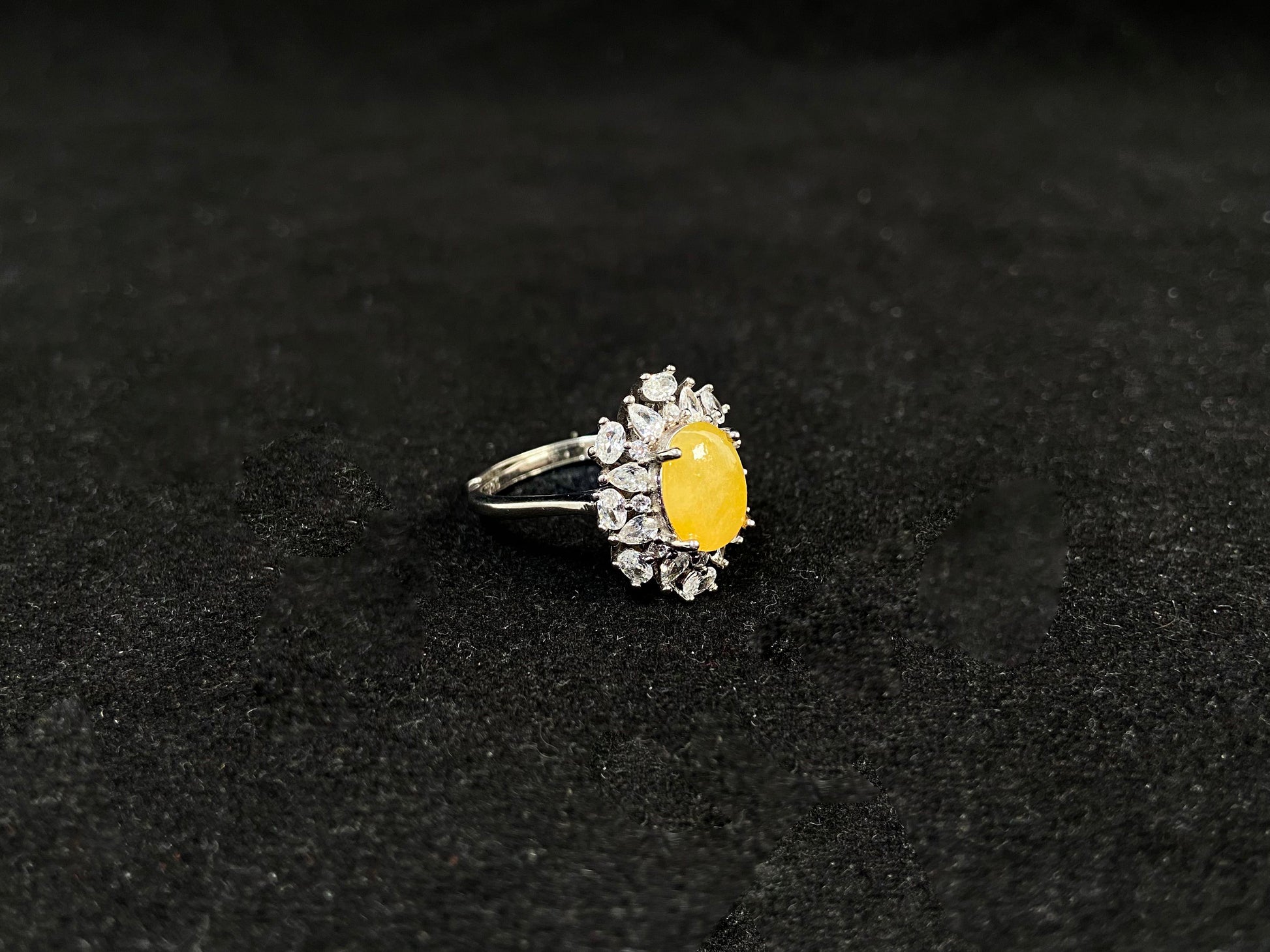 Stunning oval yellow jade is showcased in a diamond paved 925 silver setting.