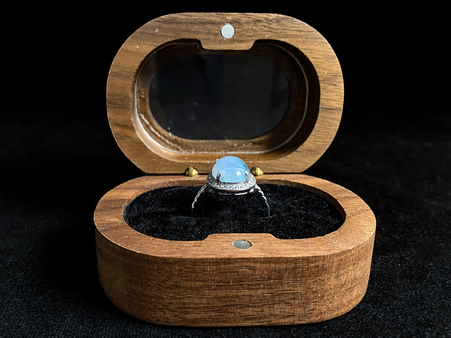 A frosty white jadeite ring featuring a deep green accent on its milky surface, crafted with prong setting to secure the circular gemstone.