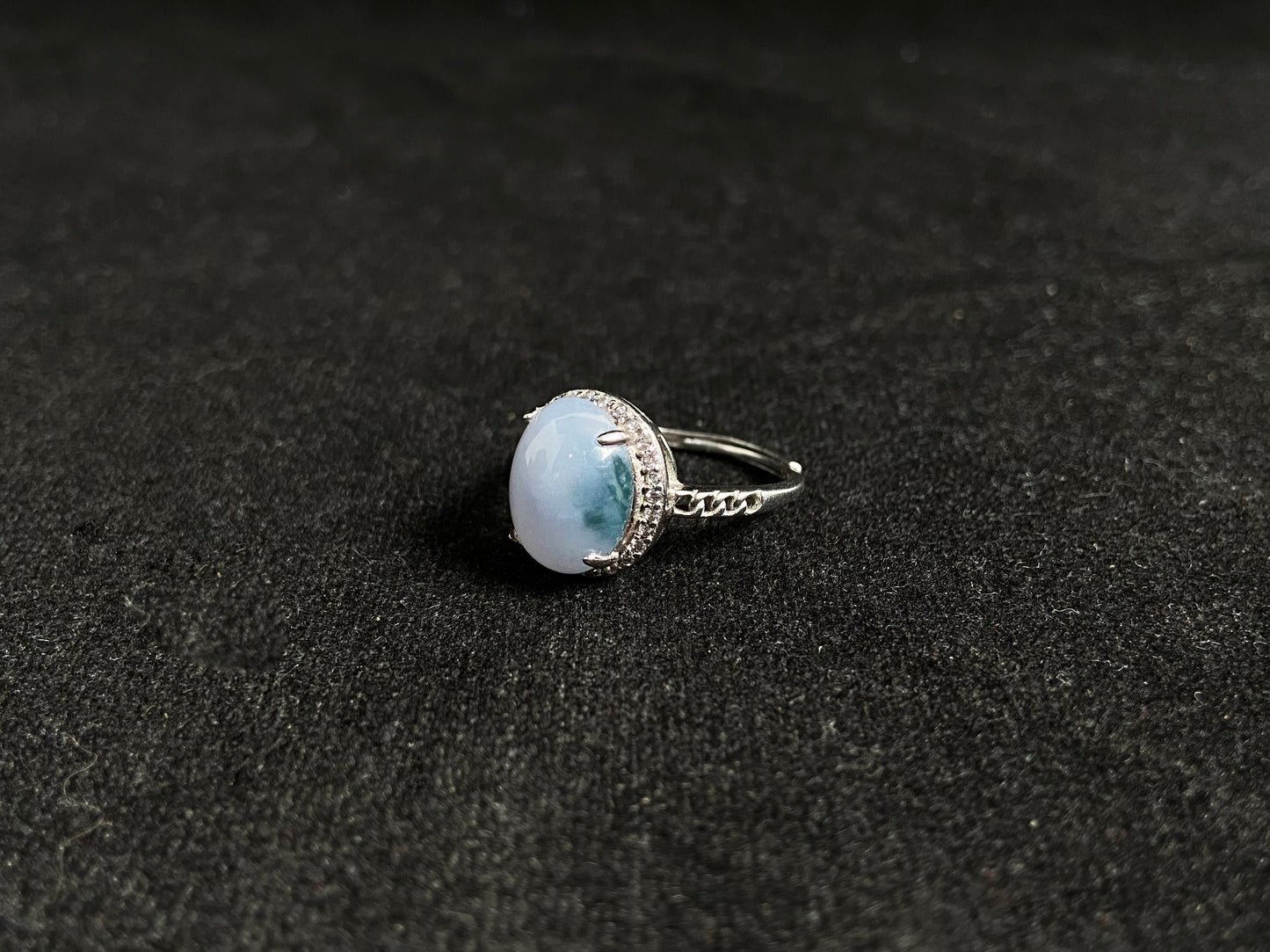 A frosty white jadeite ring featuring a deep green accent on its milky surface, crafted with prong setting to secure the circular gemstone.