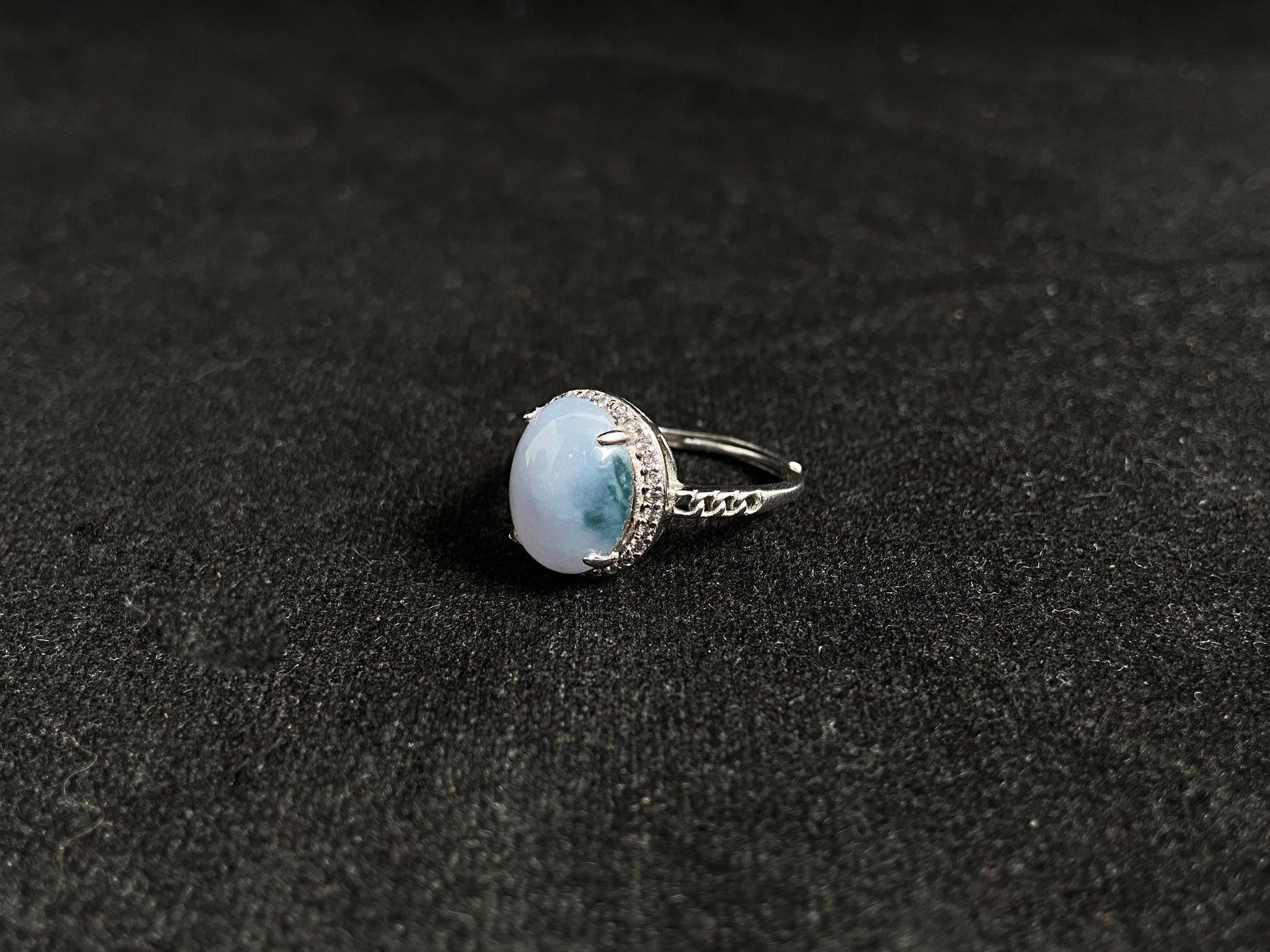 A frosty white jadeite ring featuring a deep green accent on its milky surface, crafted with prong setting to secure the circular gemstone.