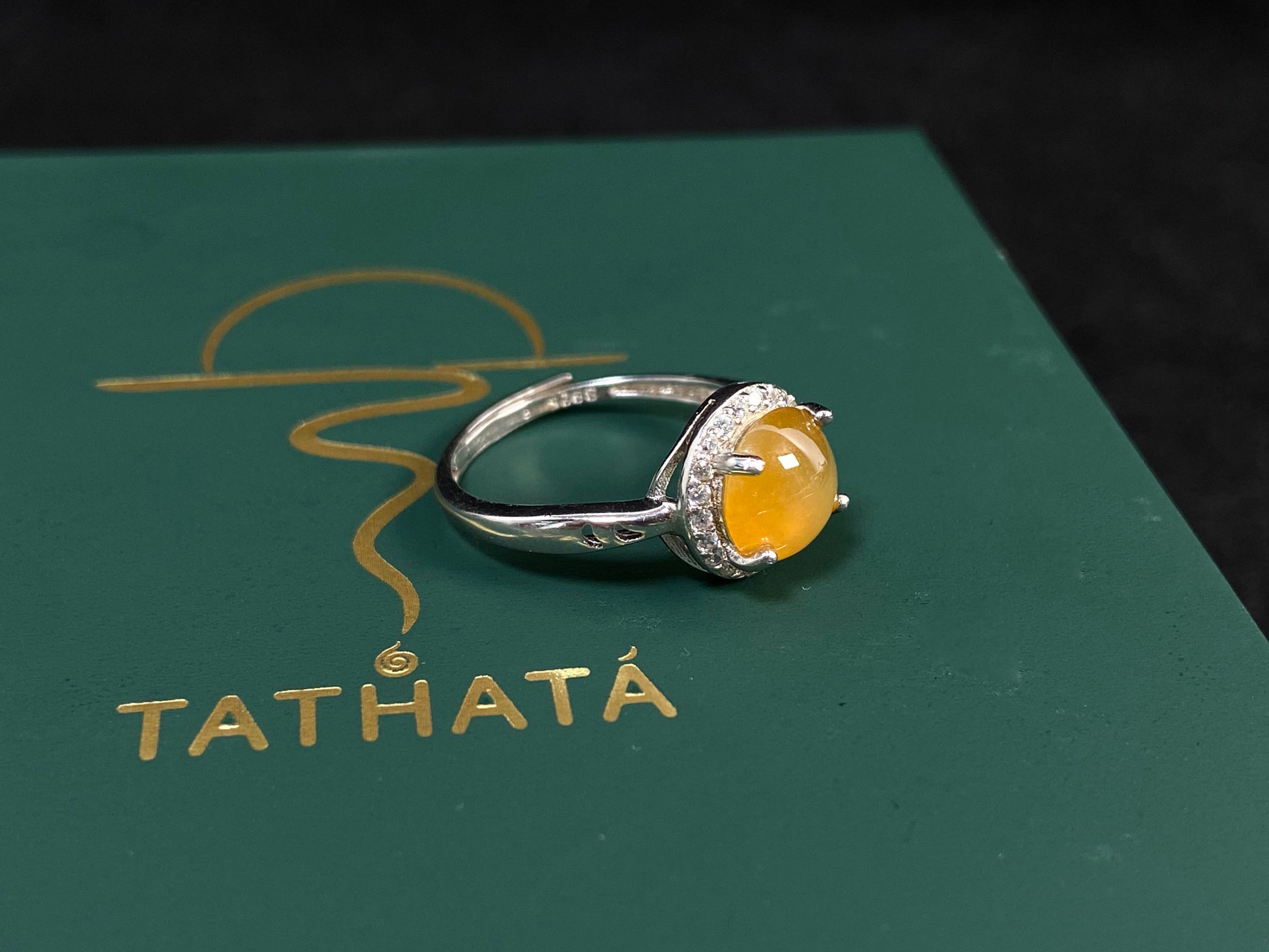 A round brown yellow jade set in 925 silver with prong setting.