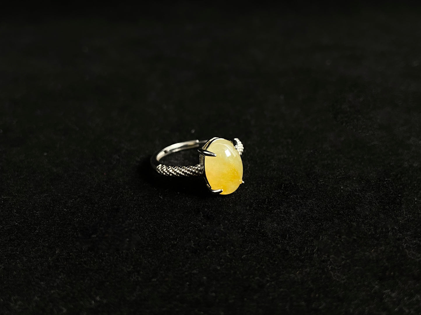 This elegant ring features an oval shaped yellow jadeite, securely set with a channel setting technique.