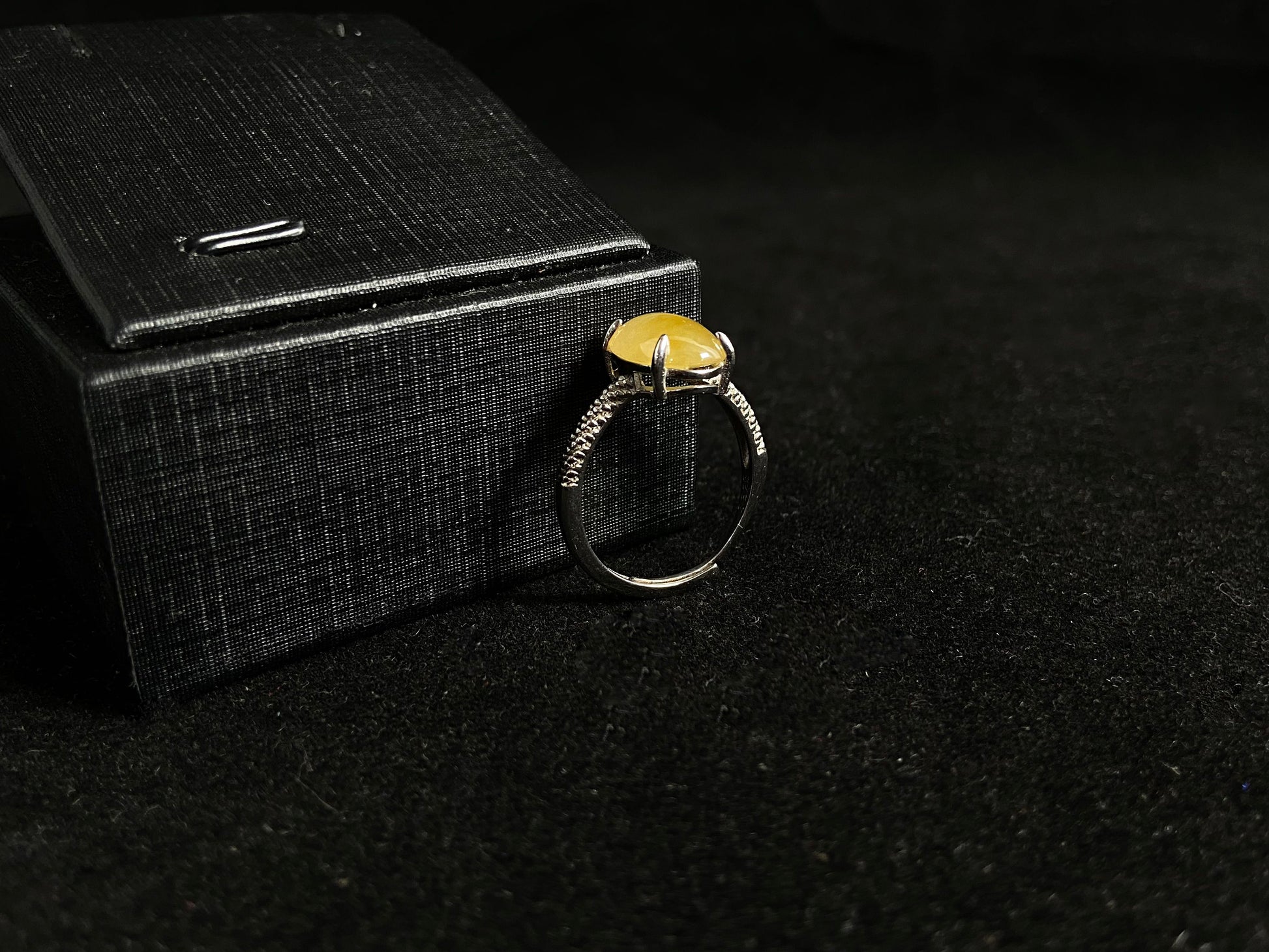 This elegant ring features an oval shaped yellow jadeite, securely set with a channel setting technique.