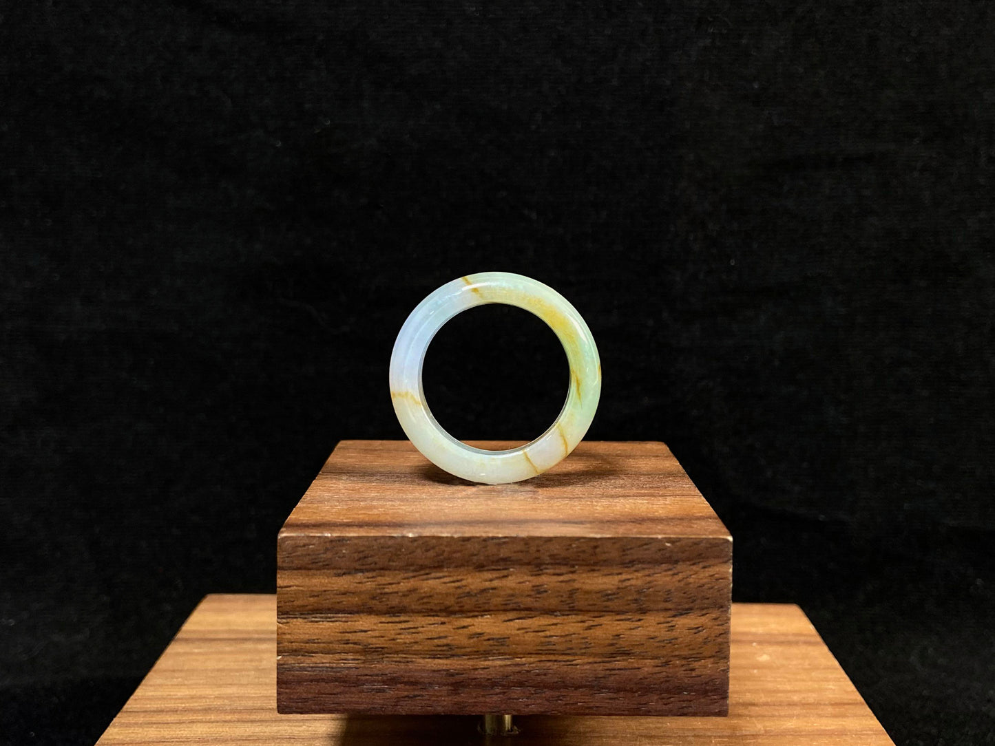 A jade bracelet in soft green, purple and white, adorned with golden streaks.