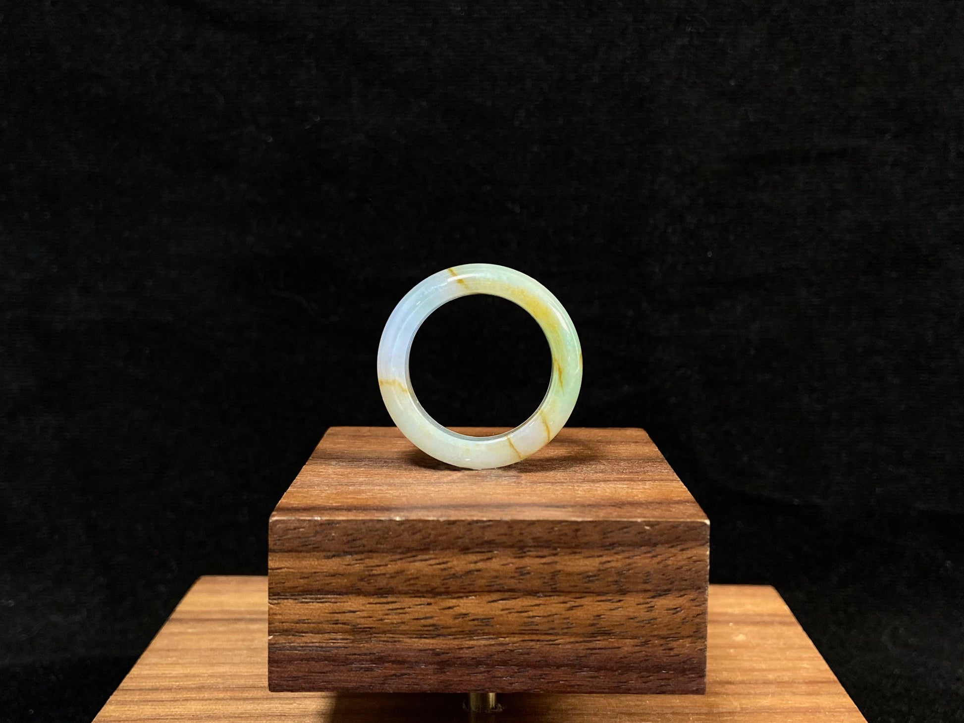 A jade bracelet in soft green, purple and white, adorned with golden streaks.