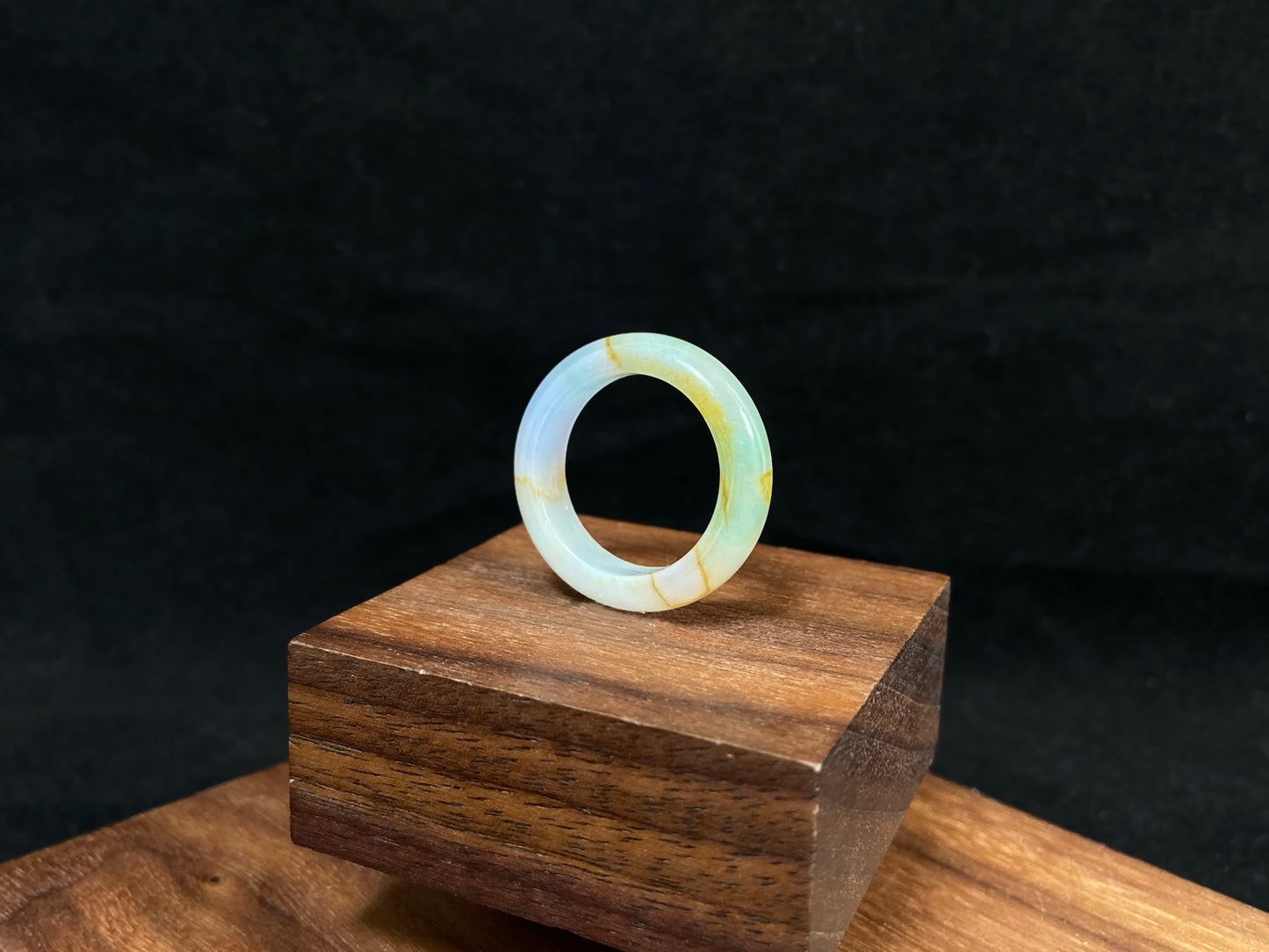 A jade bracelet in soft green, purple and white, adorned with golden streaks.