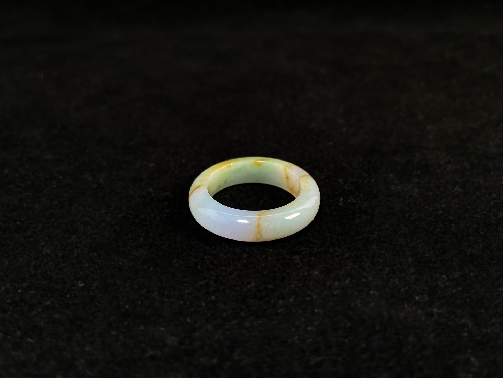 A jade bracelet in soft green, purple and white, adorned with golden streaks.