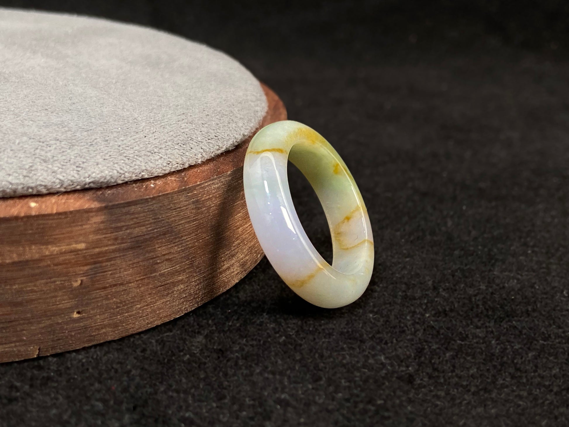 A jade bracelet in soft green, purple and white, adorned with golden streaks.