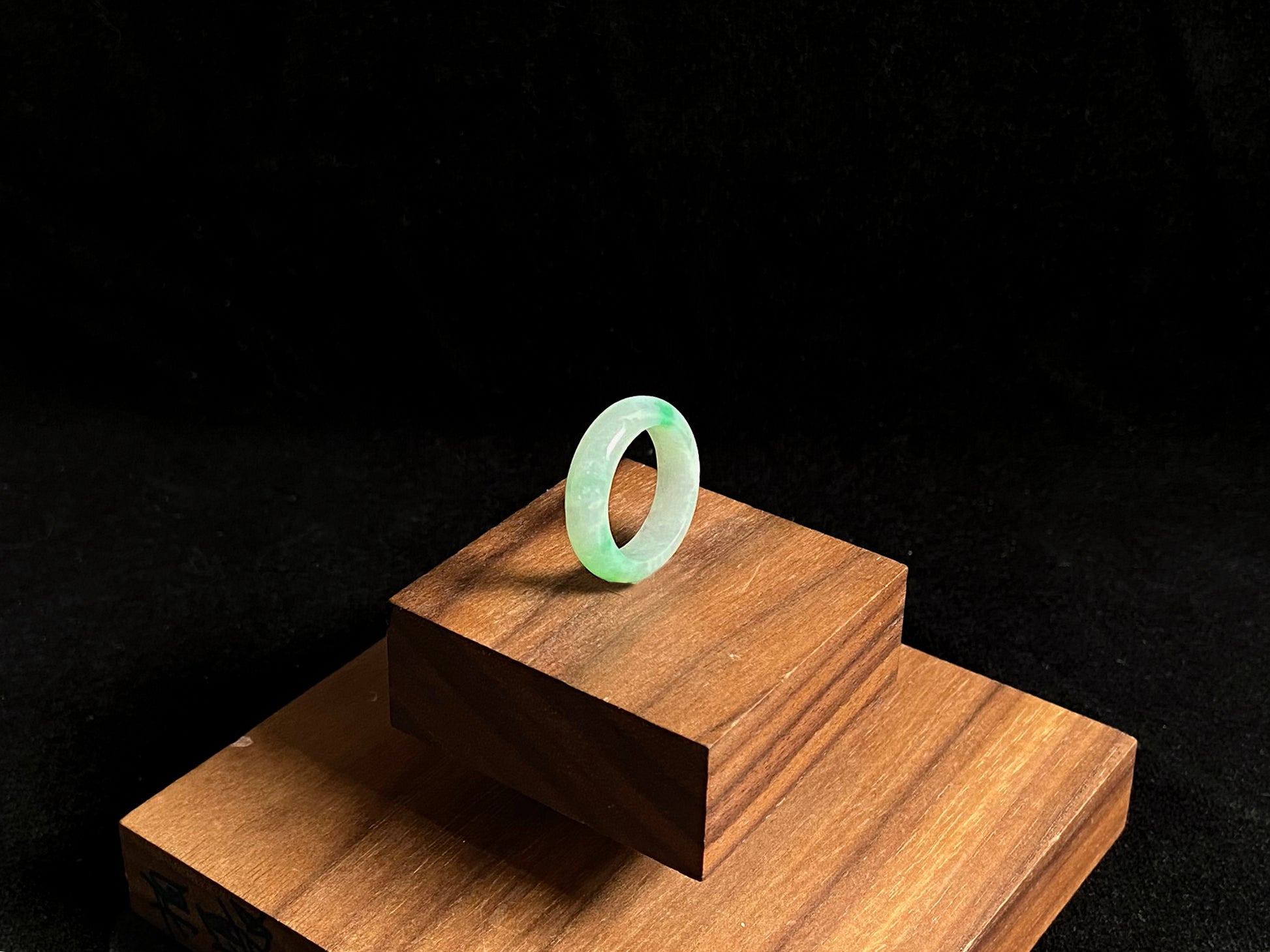 An icy white jadeite ring adorned with two accents of vibrant green.